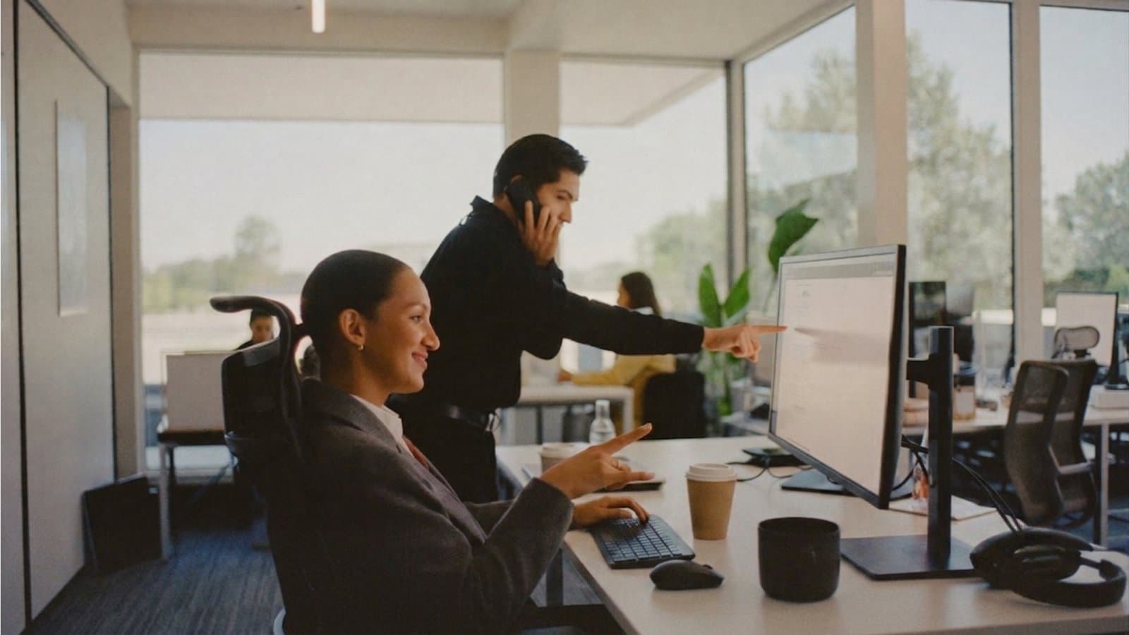 Two colleagues reviewing information together on a desktop monitor